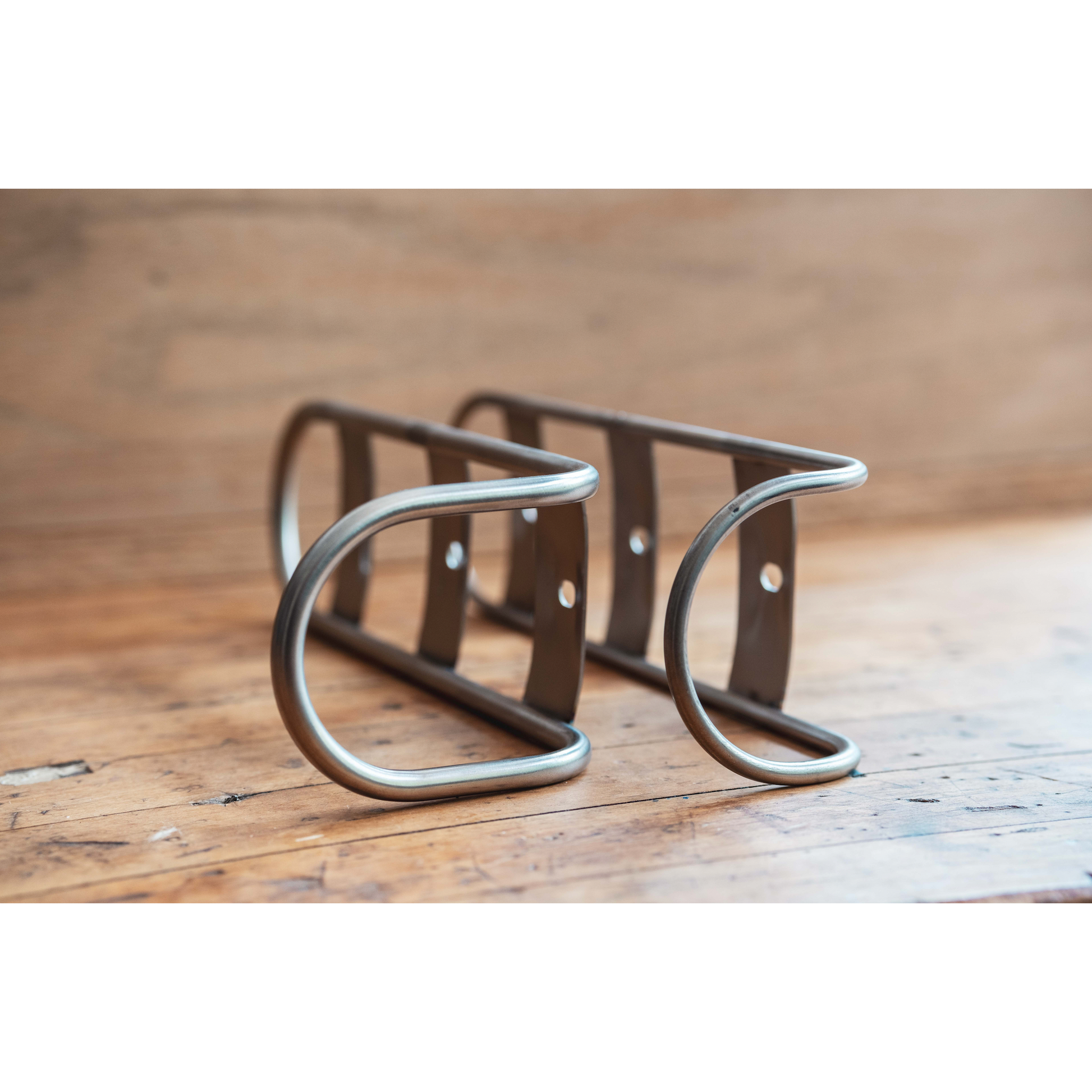 A pair of King Cage Many Things Cargo Cage in hollow rod titanium on wood floor