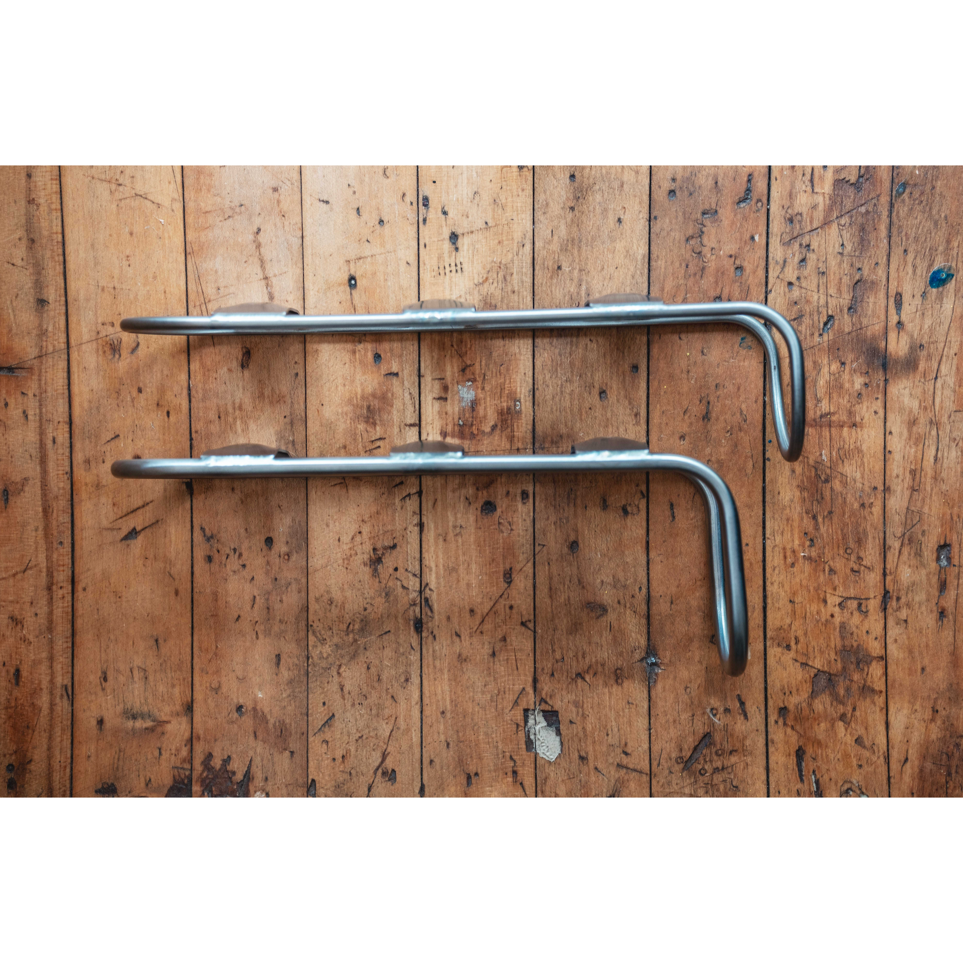 A pair of King Cage Many Things Cargo Cage in hollow rod titanium on wood floor