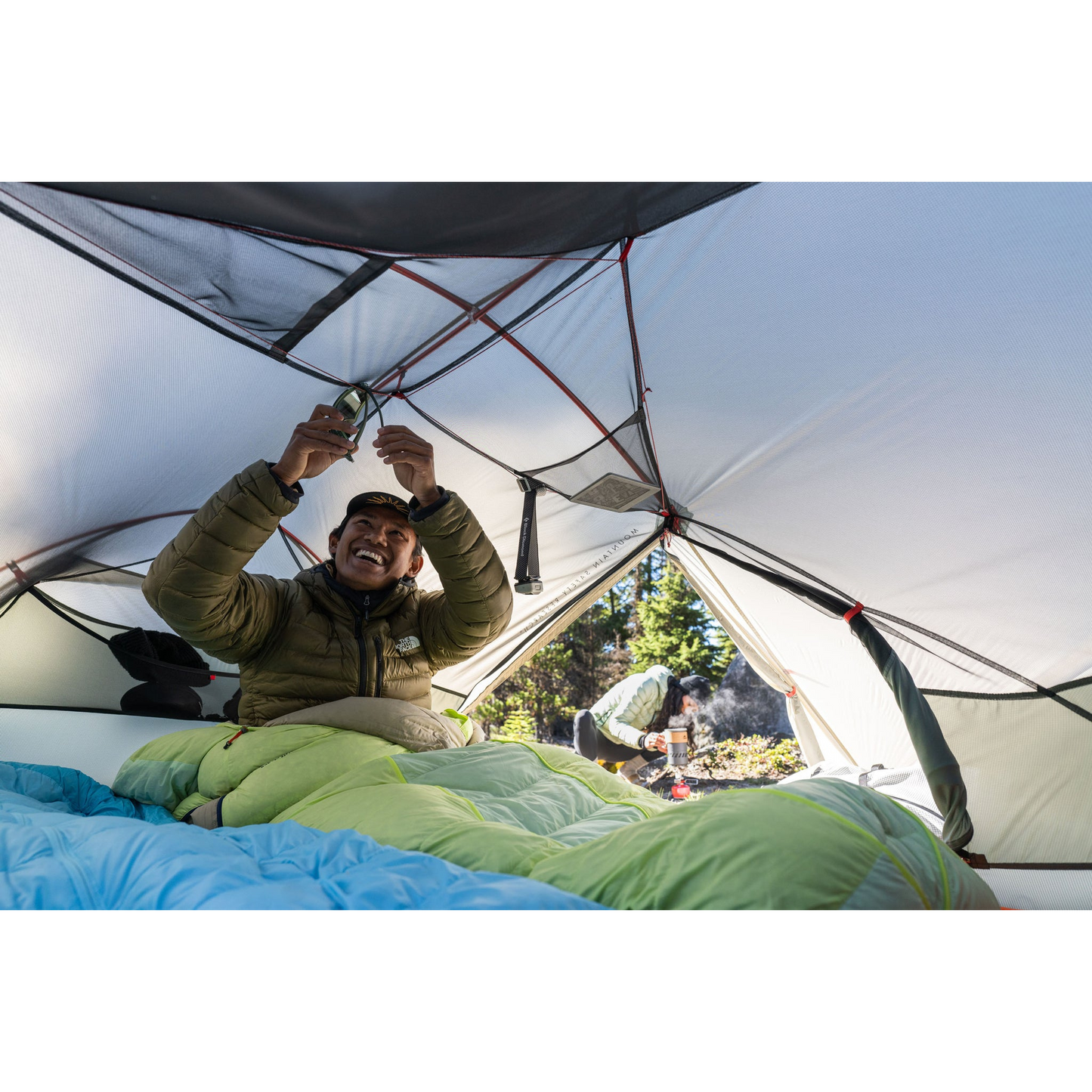 MSR Hubba Hubba LT 2‑Person Tent with one person inside hanging up gear
