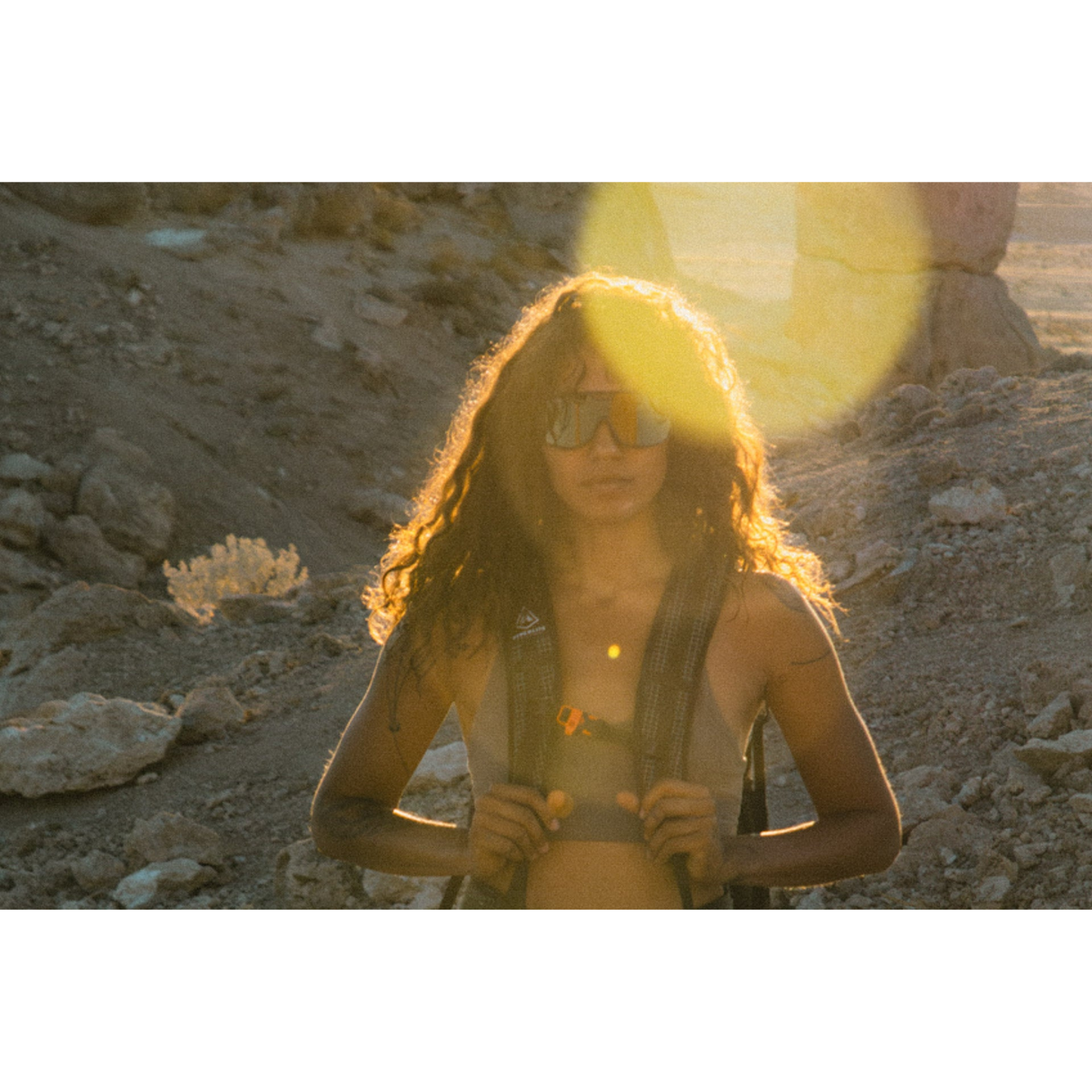 Person wearing Ombraz Refugio armless sunglasses and backpack