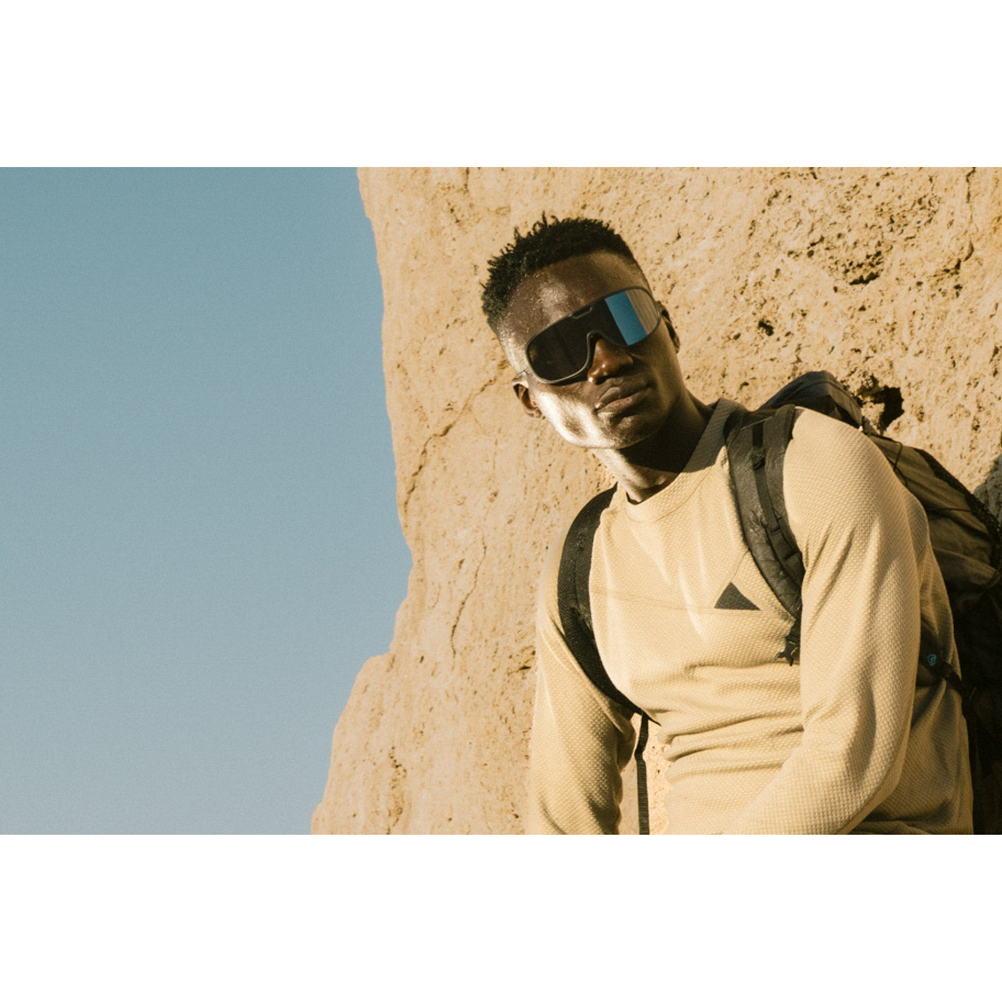 Person wearing Ombraz Refugio armless sunglasses leaning on rocky background