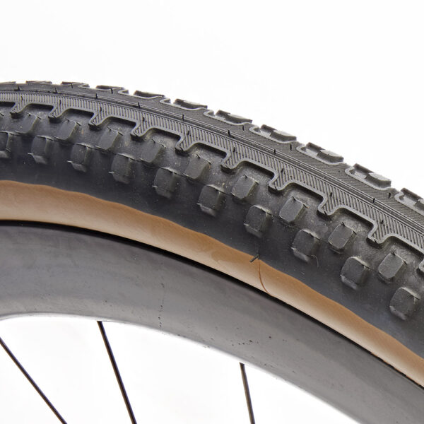 Rene Herse Poteau Mountain 700 x 48 semi-slick gravel tire with a smooth centre tread transitioning into side knobs for traction and cornering grip.