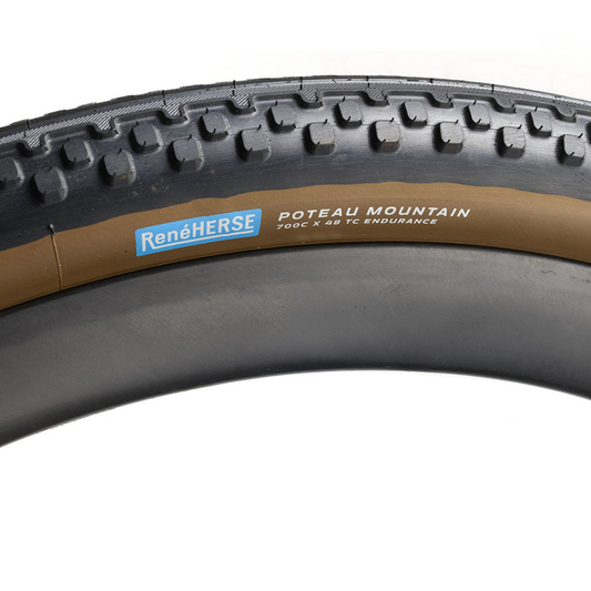 Rene Herse Poteau Mountain 700 x 48 semi-slick gravel tire with a smooth centre tread transitioning into side knobs for traction and cornering grip.