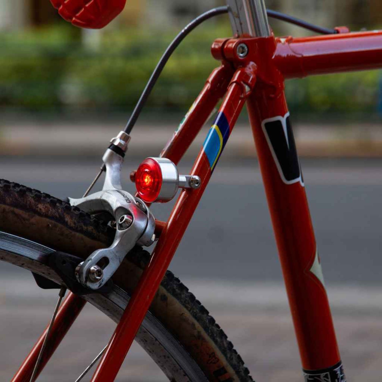 Blue Lug Koma Light Rear compact USB rechargeable bicycle taillight in silver, mounted to a red bike