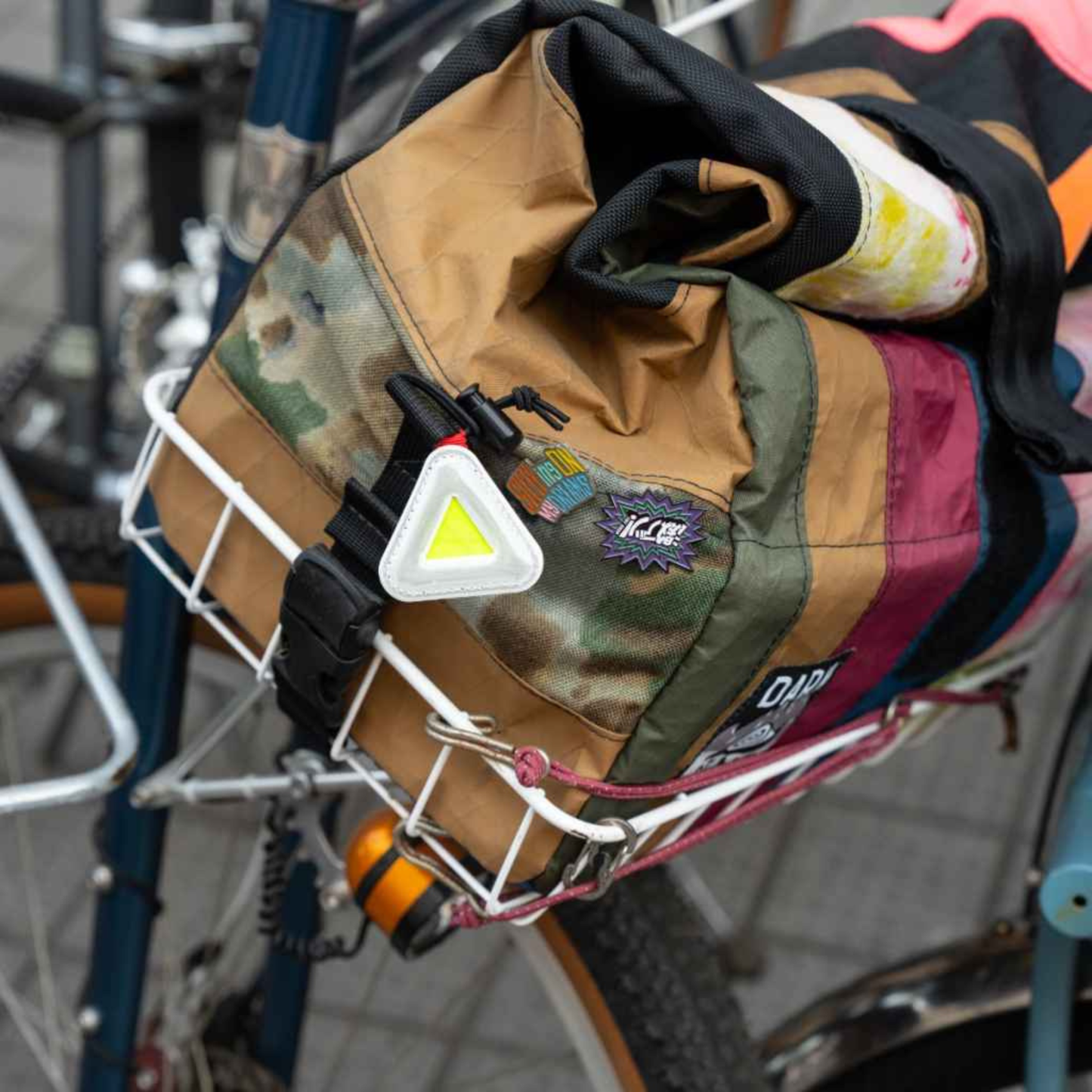 Blue Lug Mini Triangle Reflector in assorted colours mounted on a bicycle basket bag