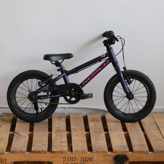 Side view of the Norco Roller 14 Kids Bike showing its small aluminum frame, training wheels, and wide 14-inch knobby tires.