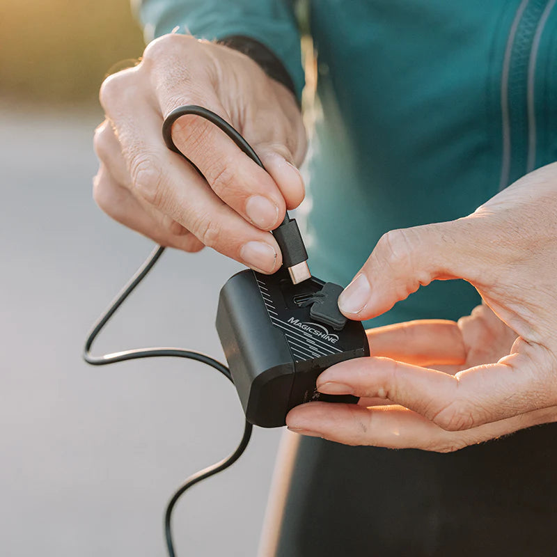Magicshine EVO 1100 with the charging cord being connected my a person