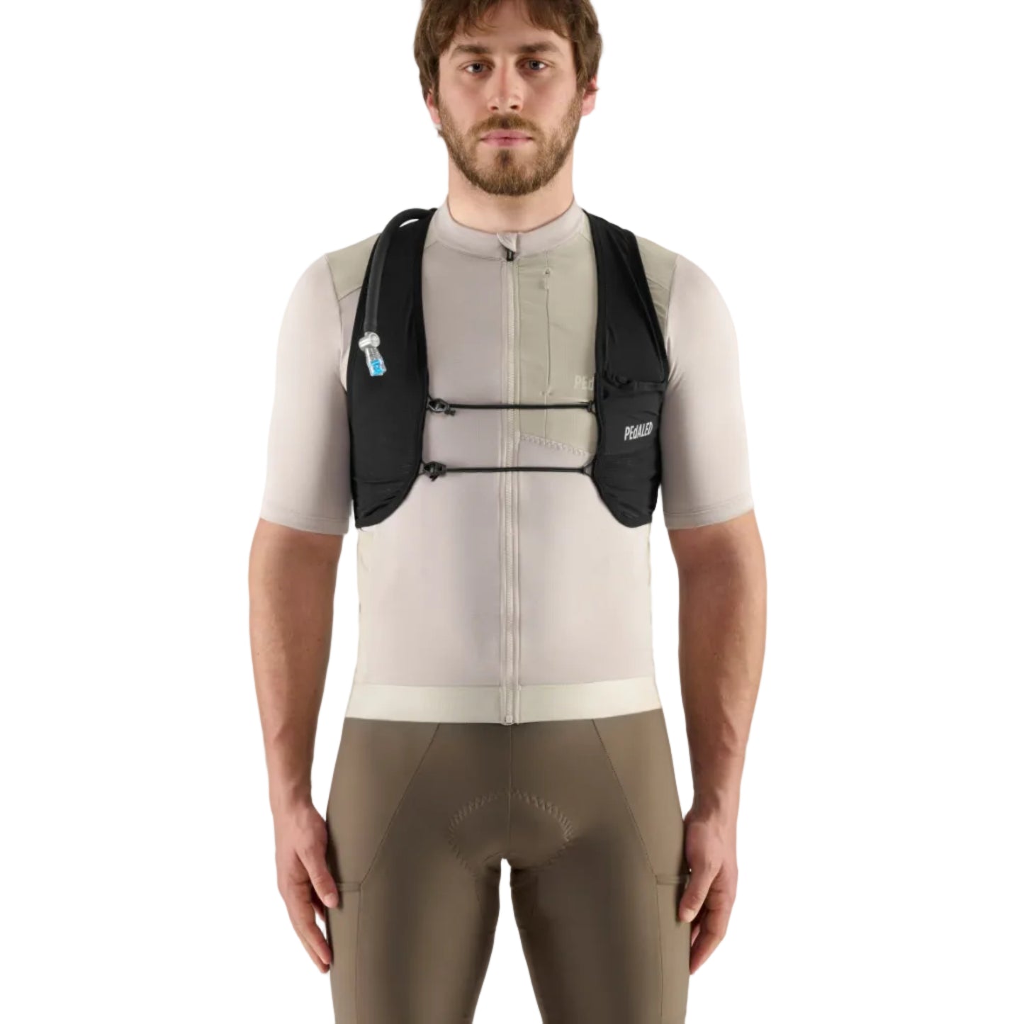 Man wearing a beige cycling jersey and brown shorts with a black hydration pack on a light gray background