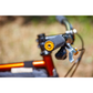 Close-up of a bicycle handlebar with a black foam grip and a Paul Bar End Cap in Gold, attached to an orange frame against a blurred outdoor background.