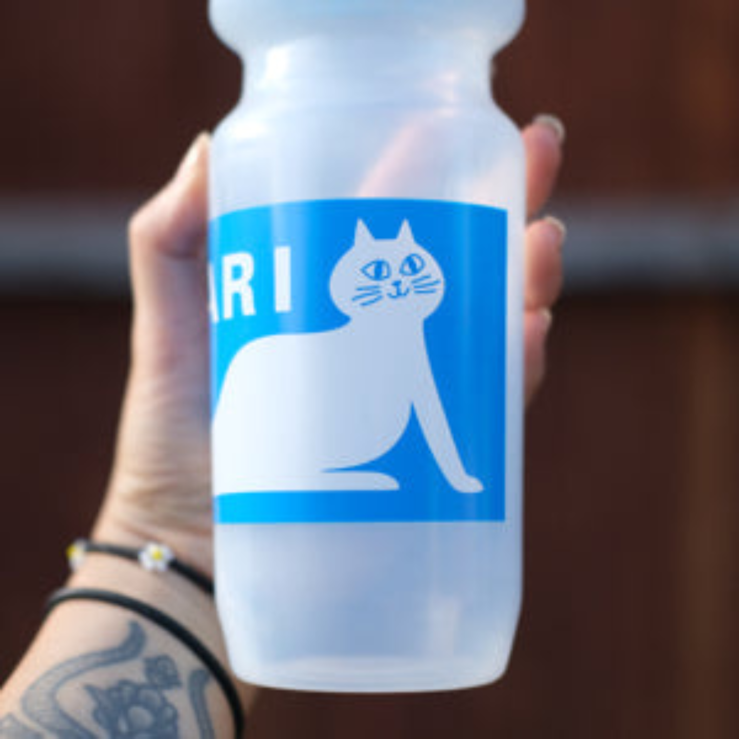 SimWorks Purrcari Sweat 24 oz water bottle being held to show the cat graphic.