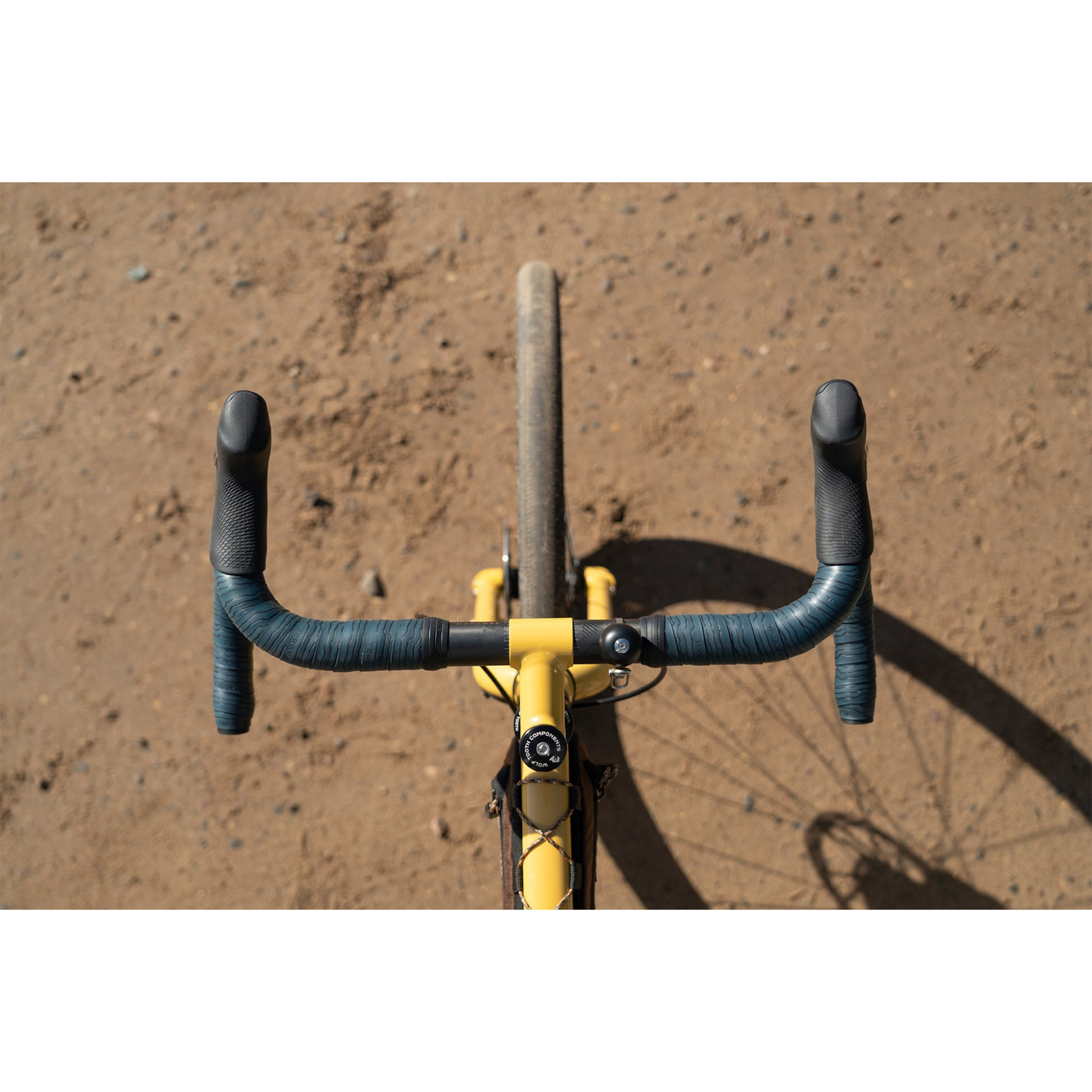 Close-up of the Teravail Radia 12 SE flared aluminum drop handlebar from above with sandy  brown background.
